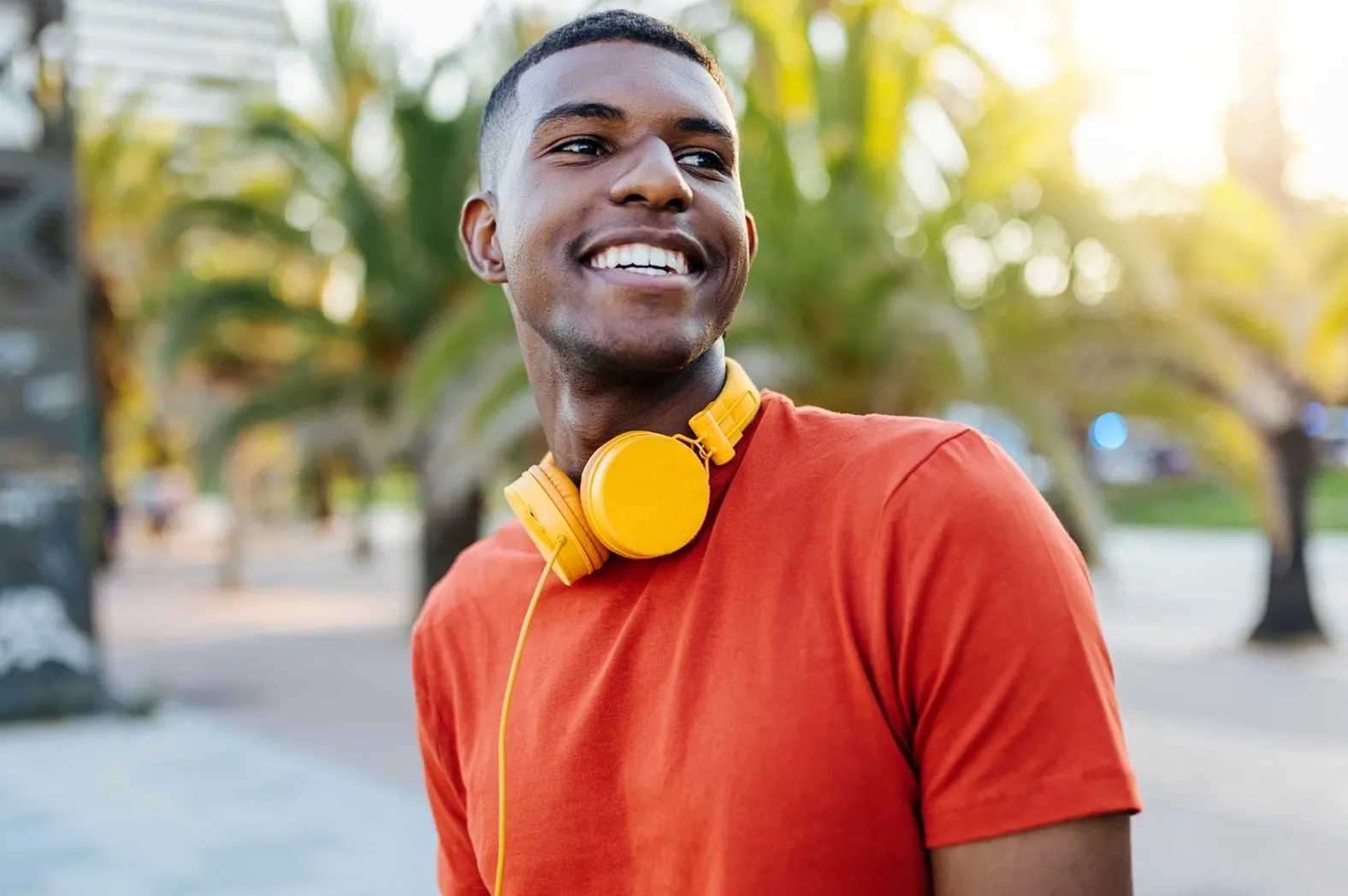 left_right-young-man-orange-shirt-yellow-headphones-outdoors