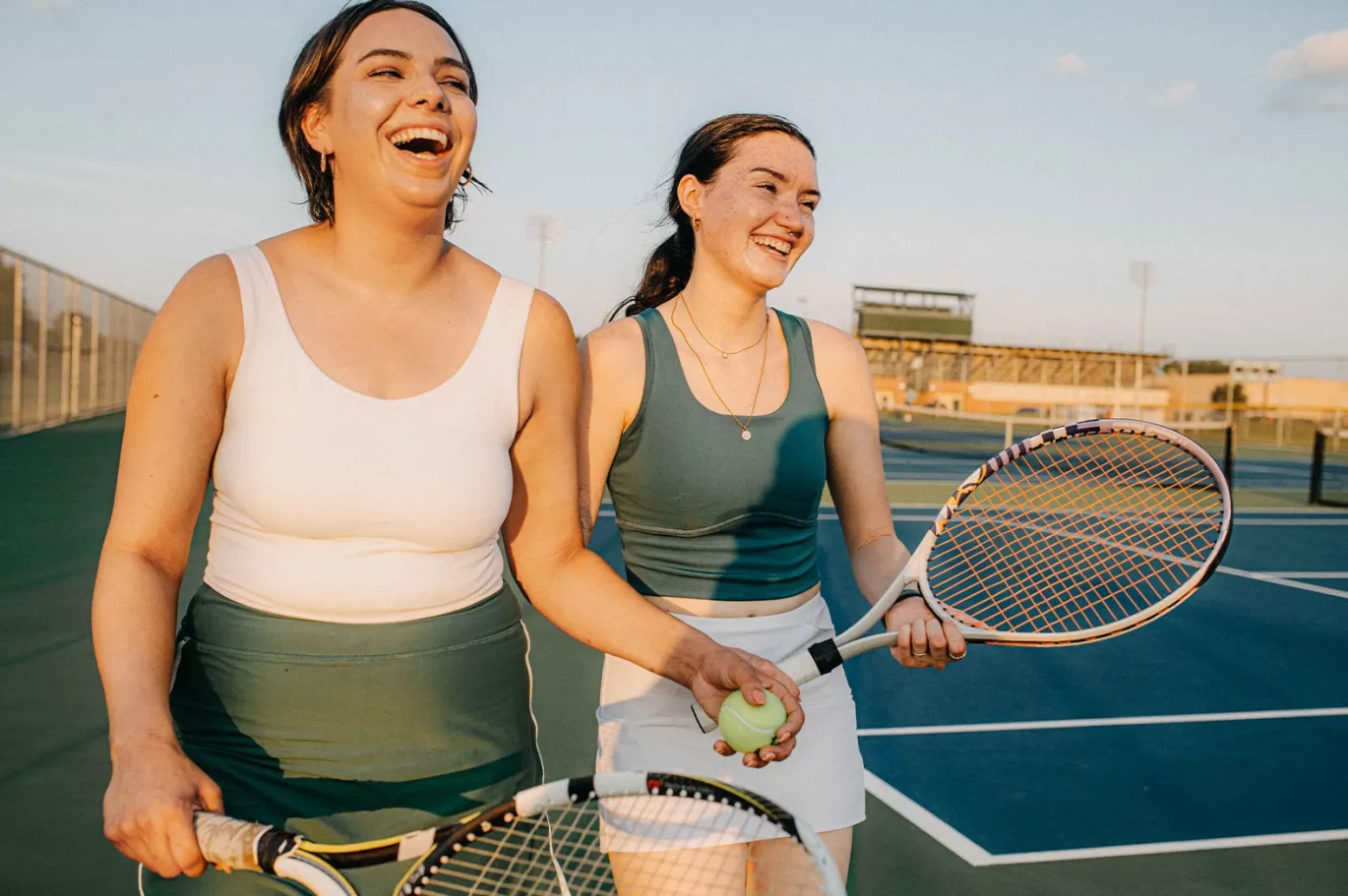 Two women playing tennis together on an outdoor court.