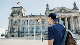 A guy carrying a backpack walks on the streets of Berlin