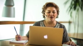 a woman with a headset in front of a laptop conducting an online speaking test