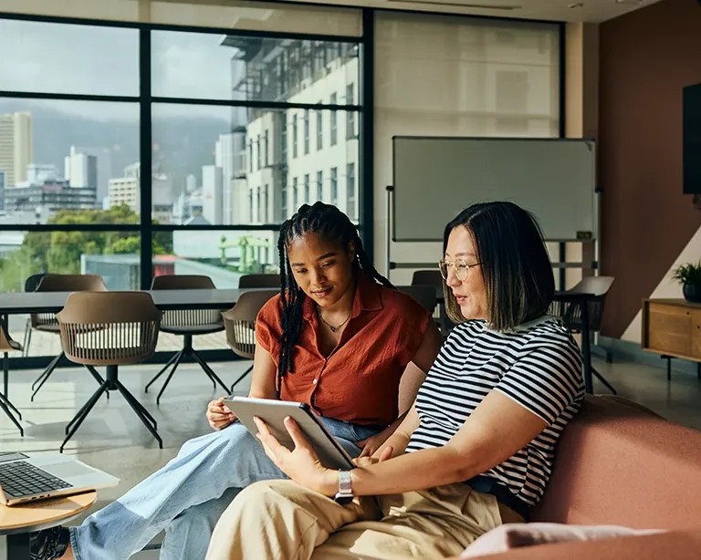 Tutor guiding an IELTS test taker during a study session with a laptop and tablet