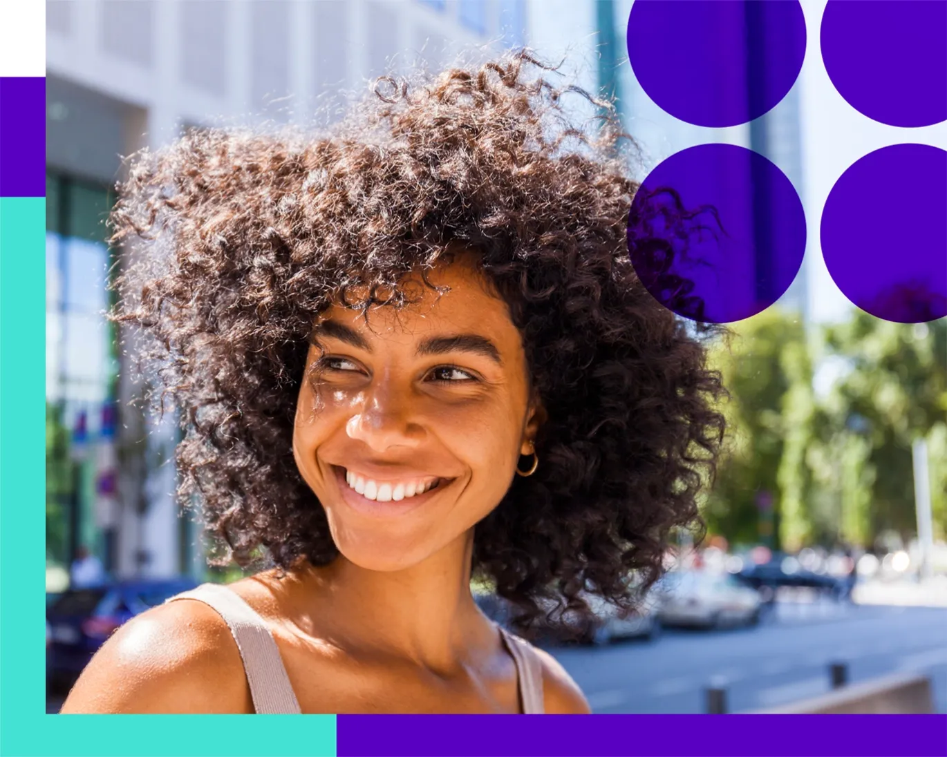 Curly hair girl smiling outdoors infront of modern building.