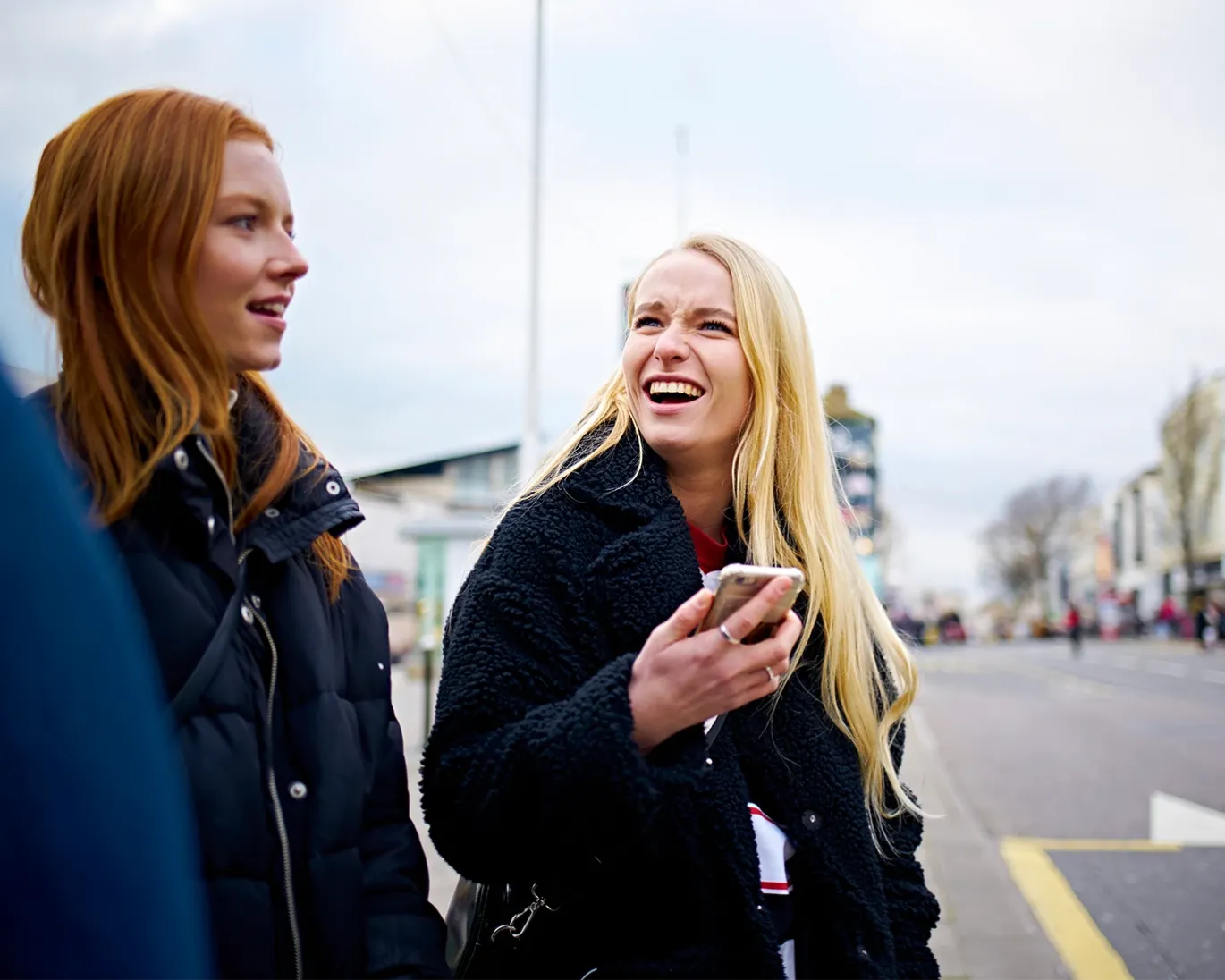 Friends chatting outdoors while checking a mobile phone