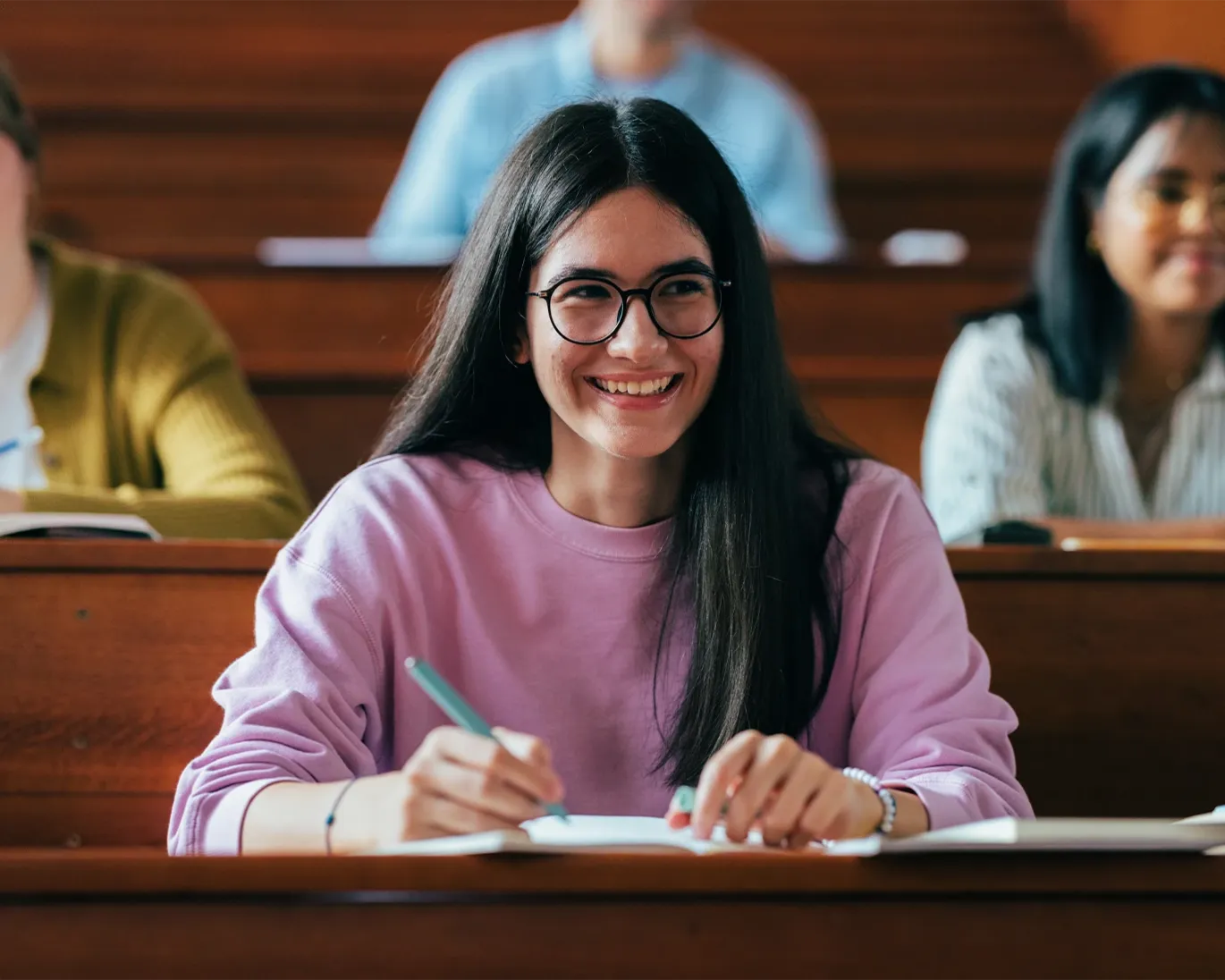 A girl taking notes while sitting in a classroom