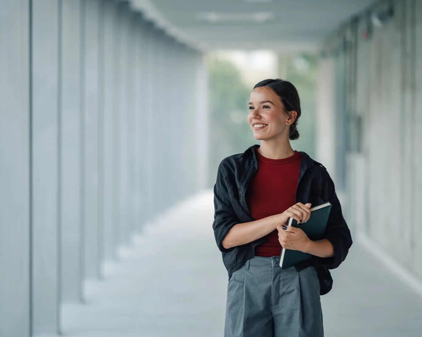 Young man holding IELTS study materials while walking through a modern hallway.
