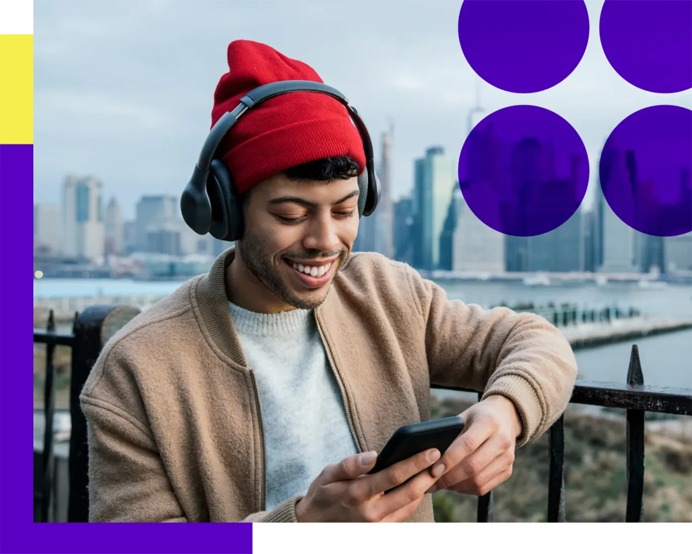 Young man wearing a winter hat while using her mobile phone near a city waterfront.