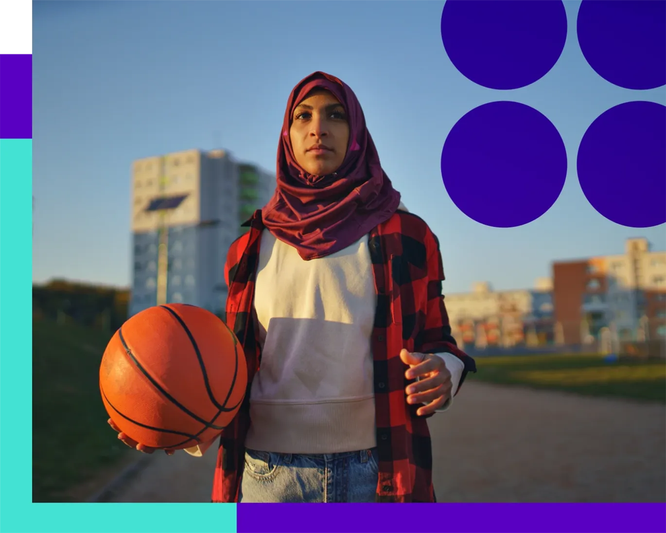 Young woman holding a basketball while standing outdoors in a city.