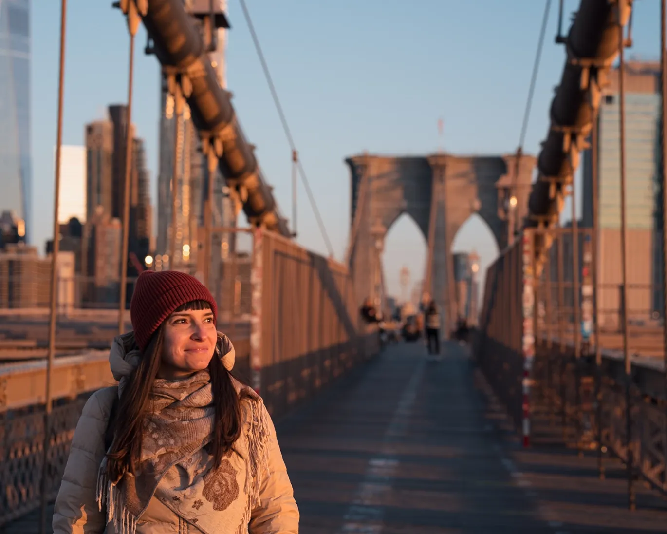 Young woman walking across a city bridge.
