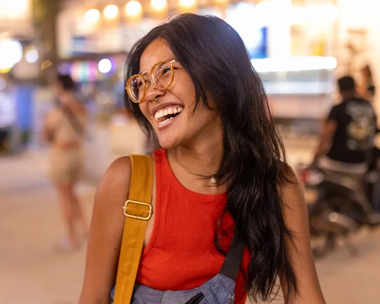 Young woman smiling while walking through a city street at night.