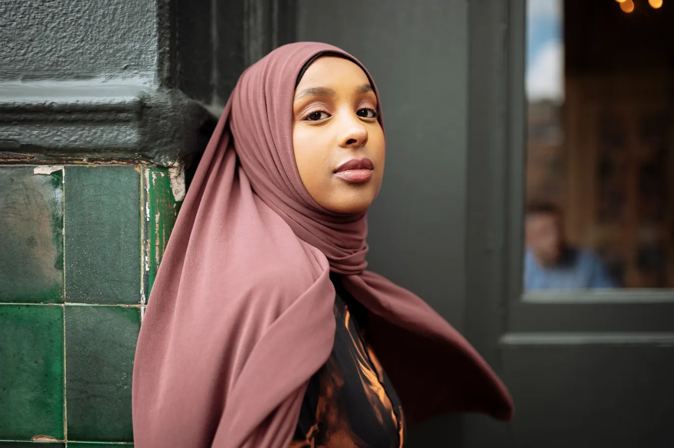 Young woman wearing a hijab while standing outdoors in the city.