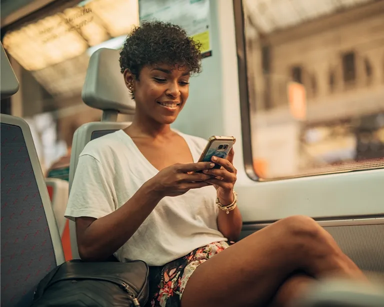 Young woman using her mobile phone while traveling on a train.
