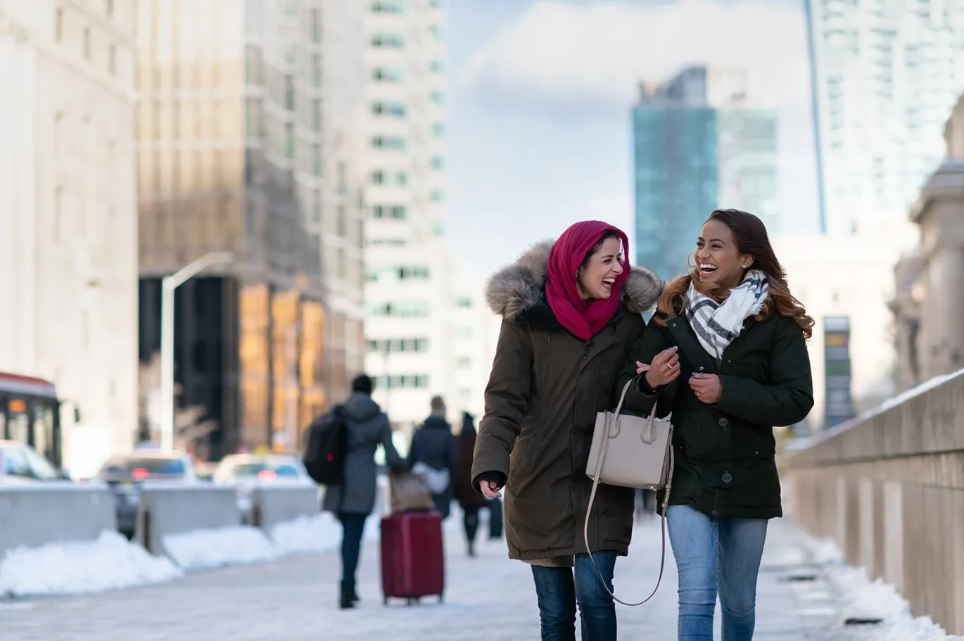 Two friends walking together and talking on a snowy city street