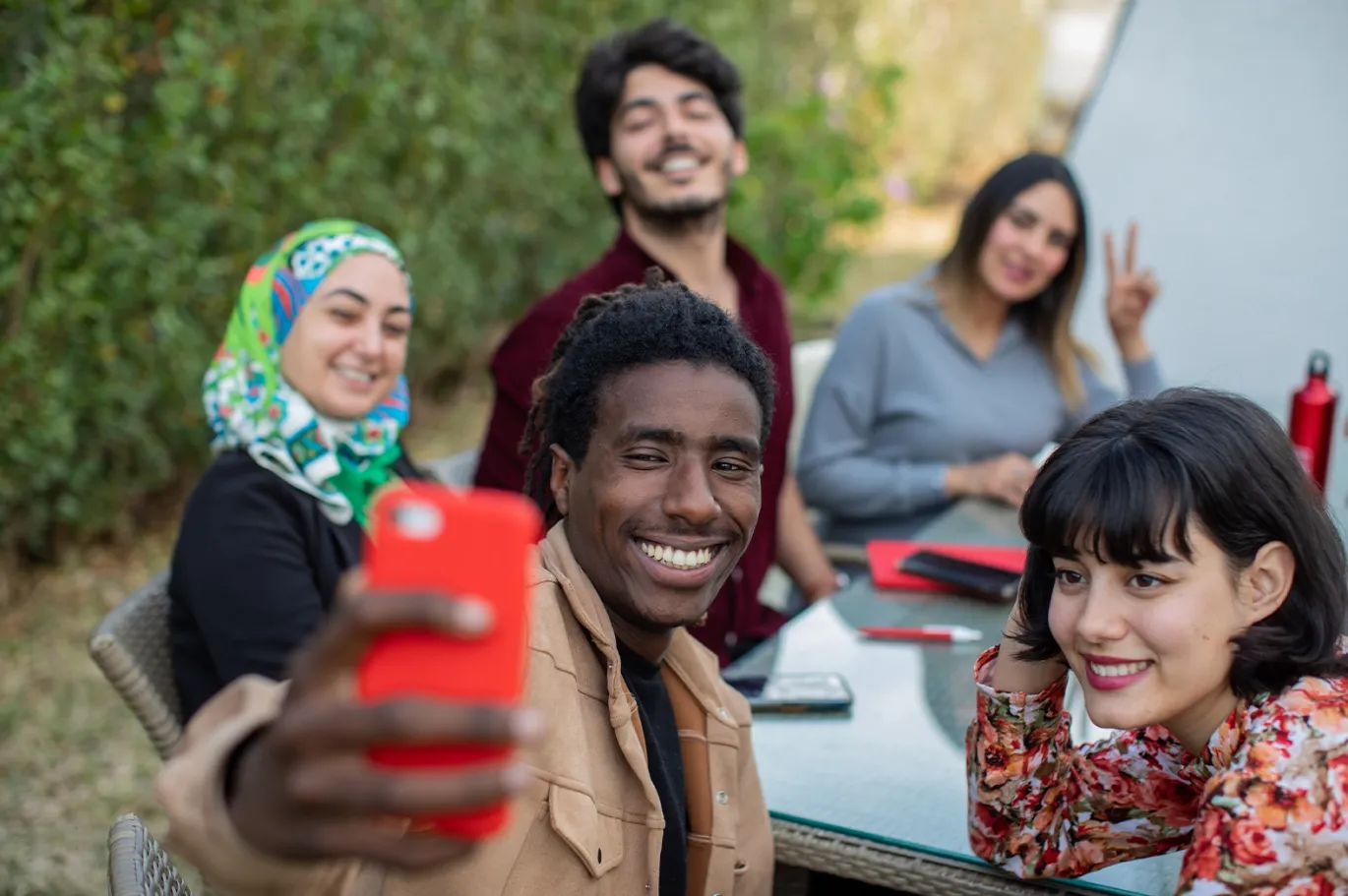 Group of friends taking a selfie together outdoors in a park.