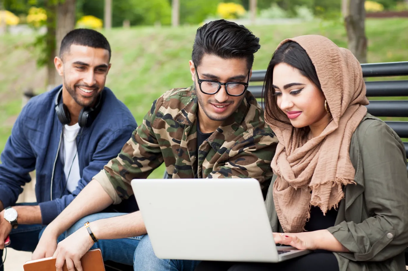 Group of students studying together for the IELTS exam using a laptop.