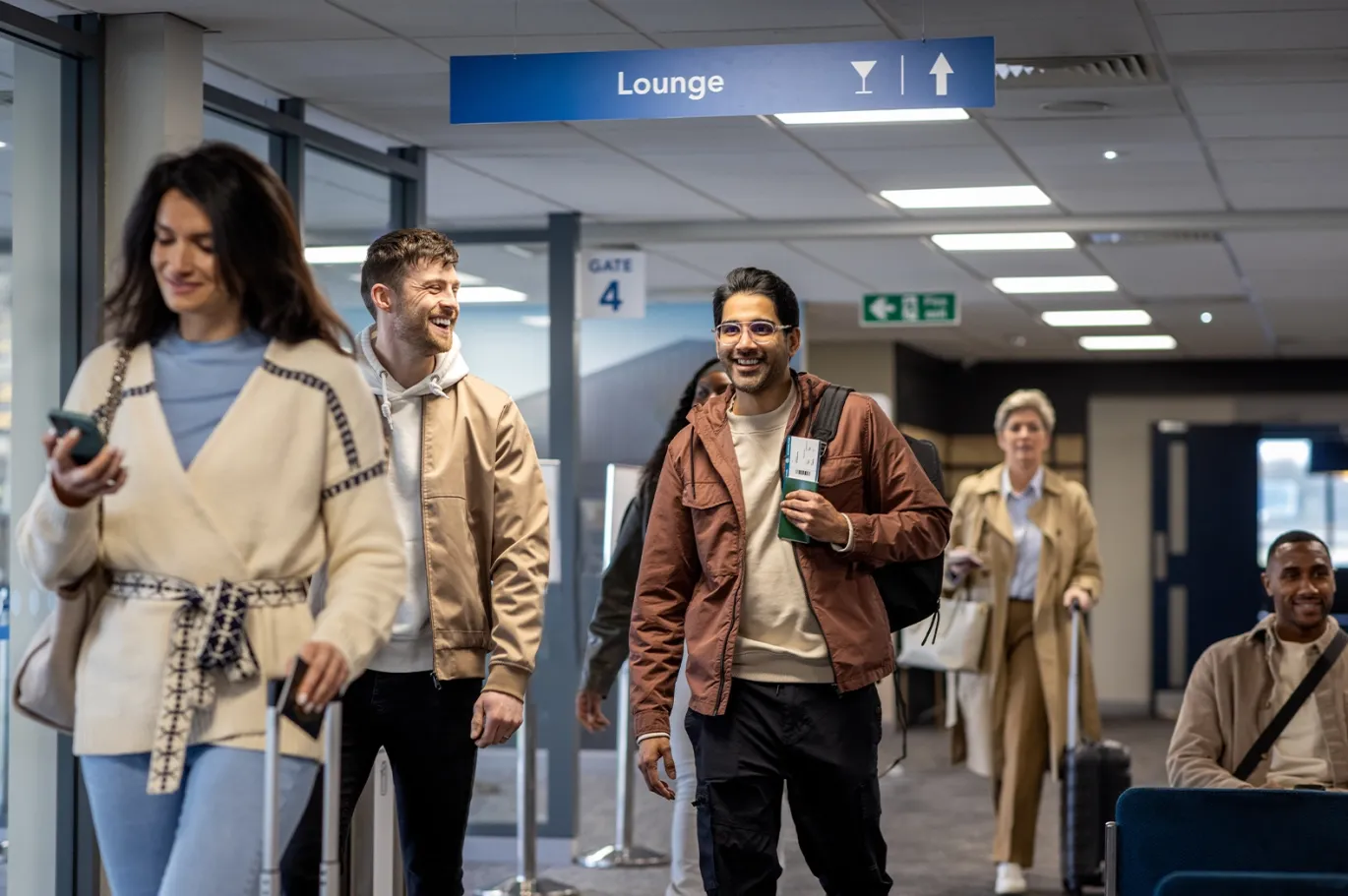 Group of travelers walking through an airport terminal with luggage.