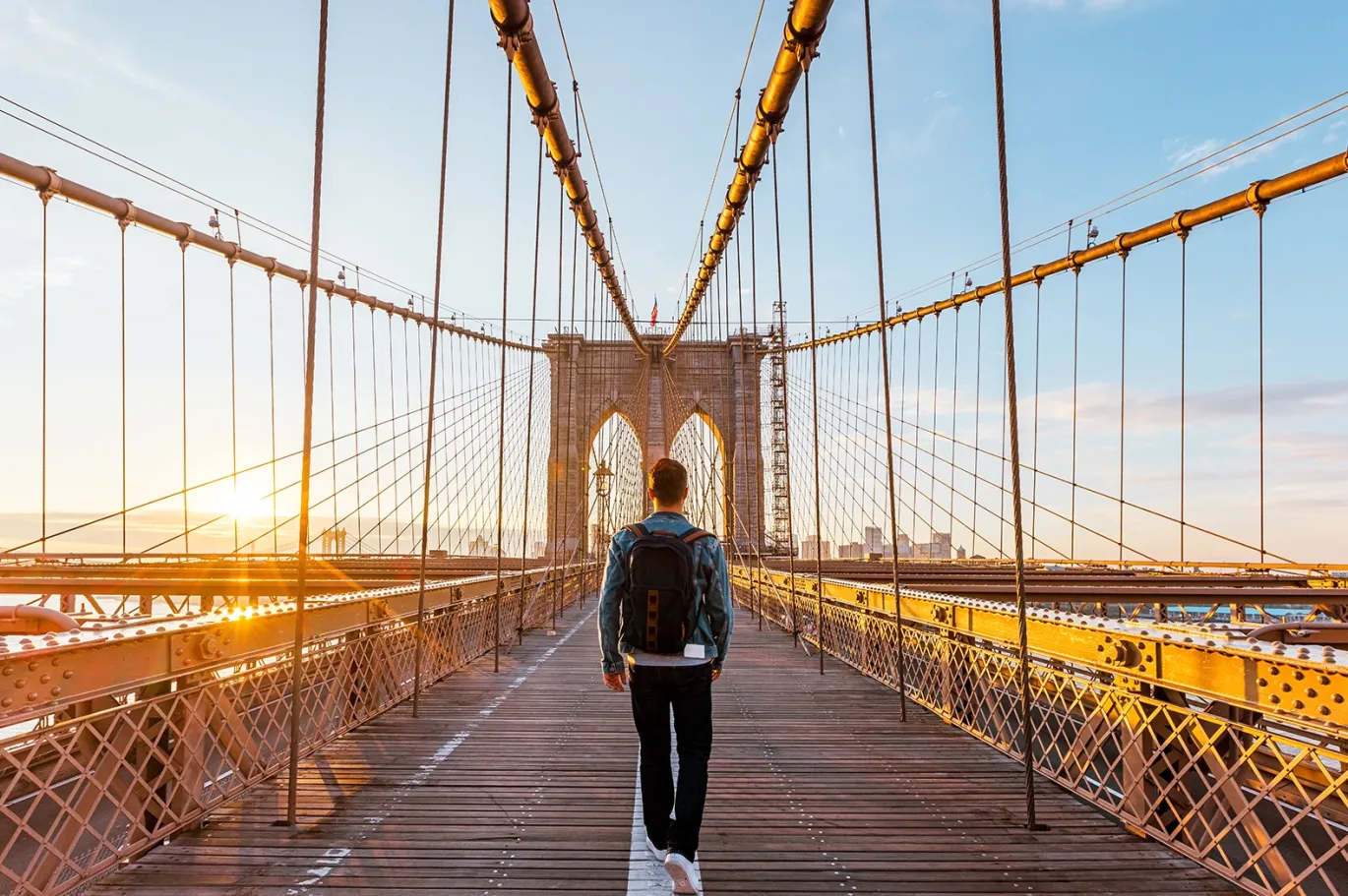 Person walking across a city bridge during sunset.