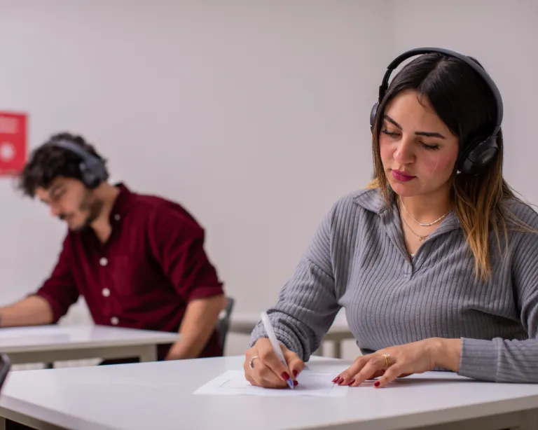 Test takers writing the IELTS exam while sitting in a classroom.