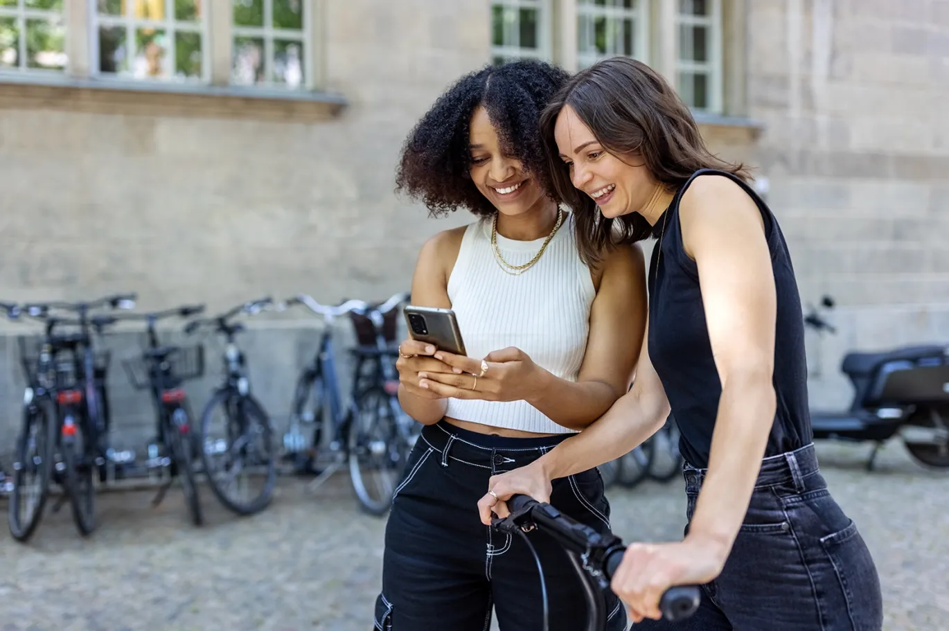 Two friends discussing IELTS study materials while checking notes outdoors.