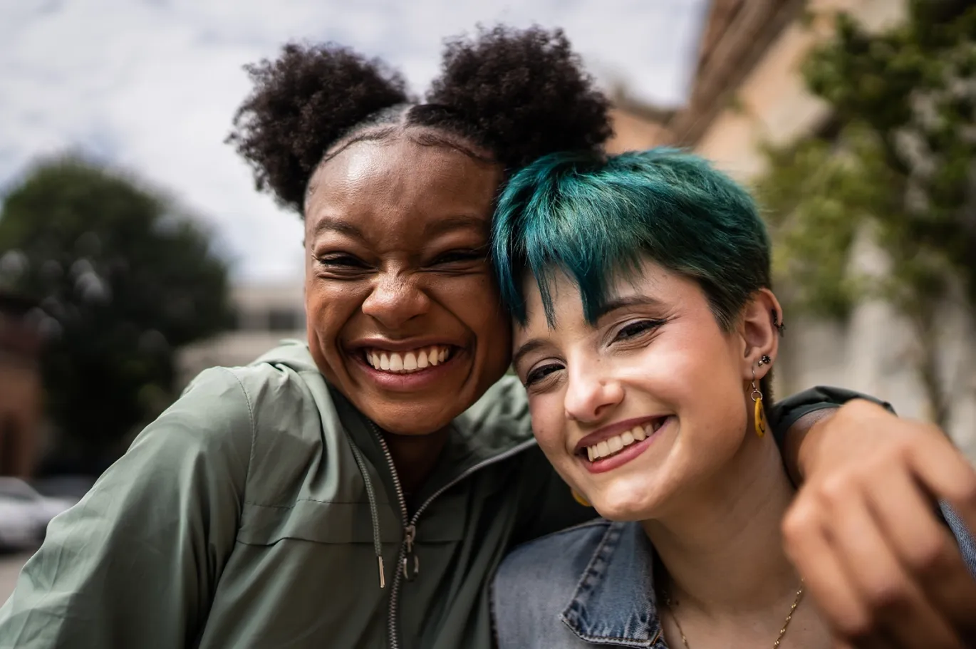 Two friends smiling together outdoors for a selfie.