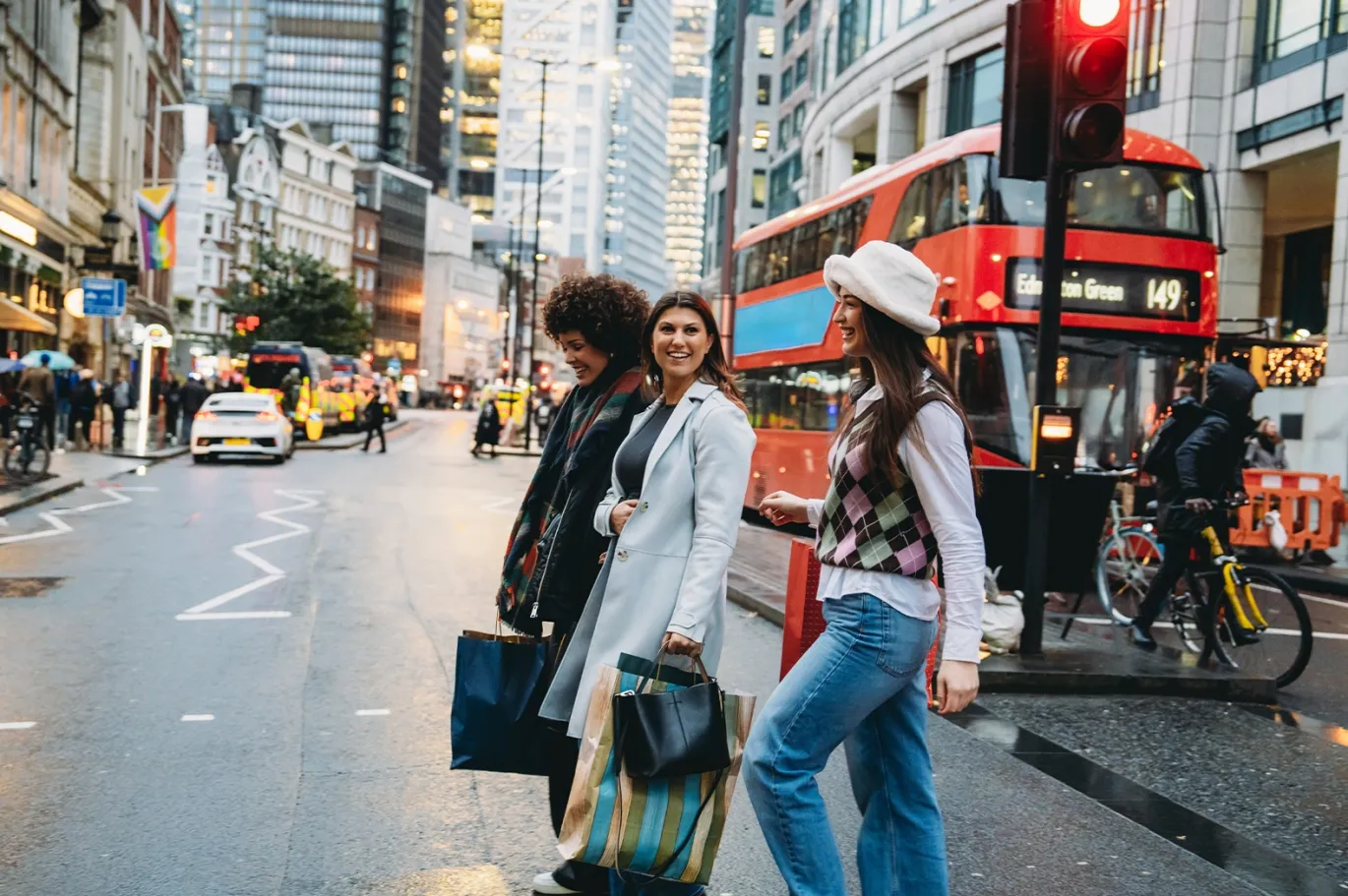 Two friends walking through a busy city street with shopping bags.