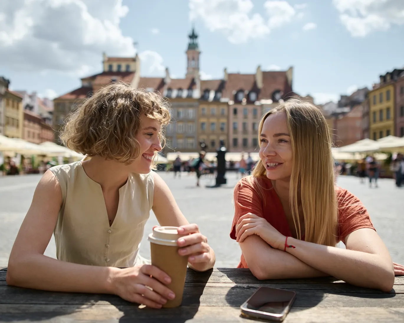 Two friends talking at an outdoor cafe in a European city