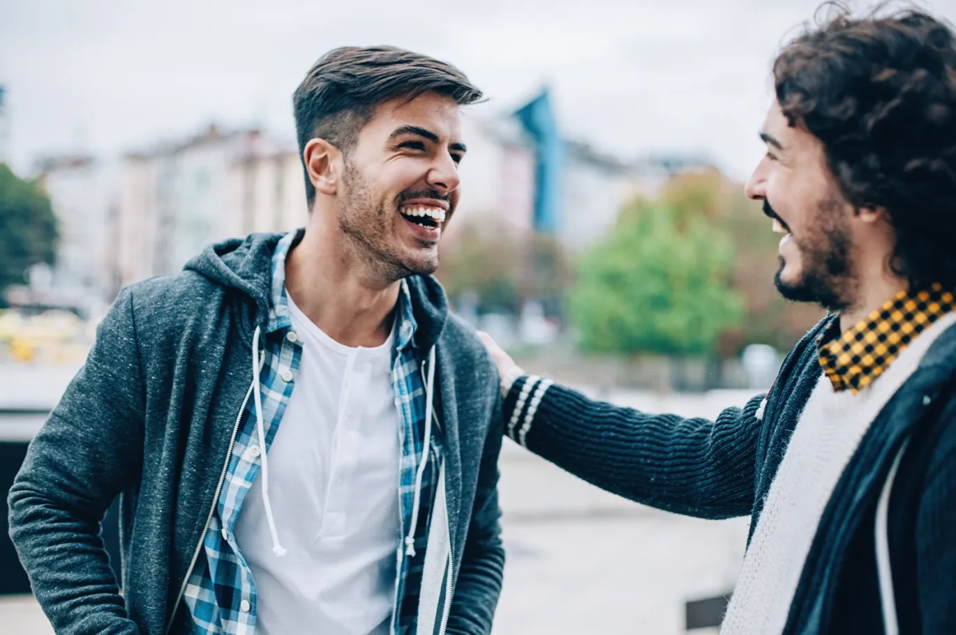 Two friends smiling and talking together outdoors.