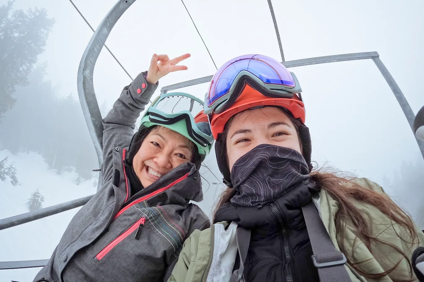 Two friends in winter jackets taking a selfie outdoors in snowy weather.