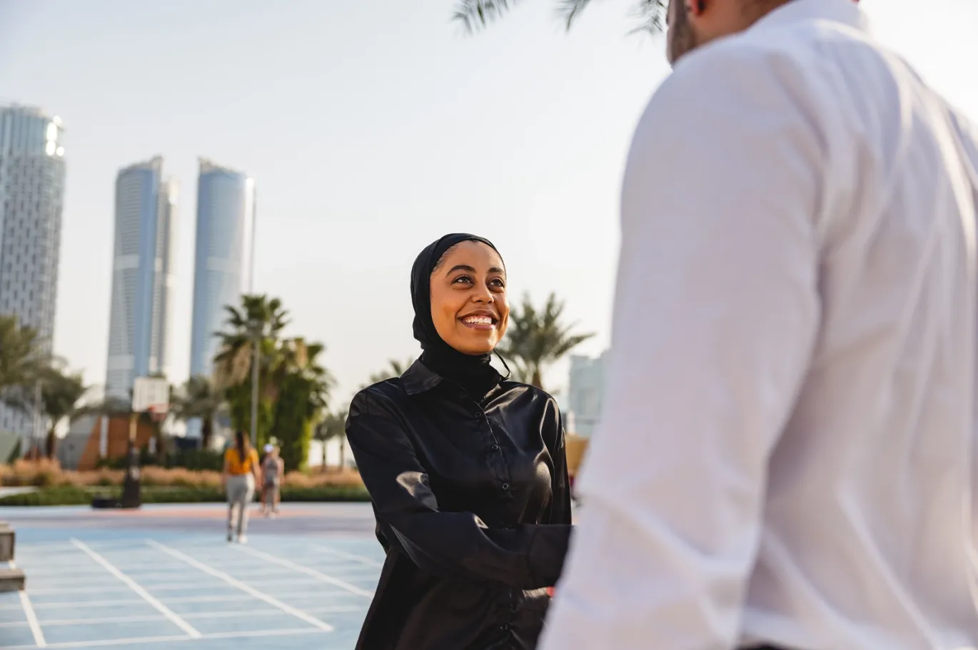 Woman standing and talking outdoors in a modern city setting.