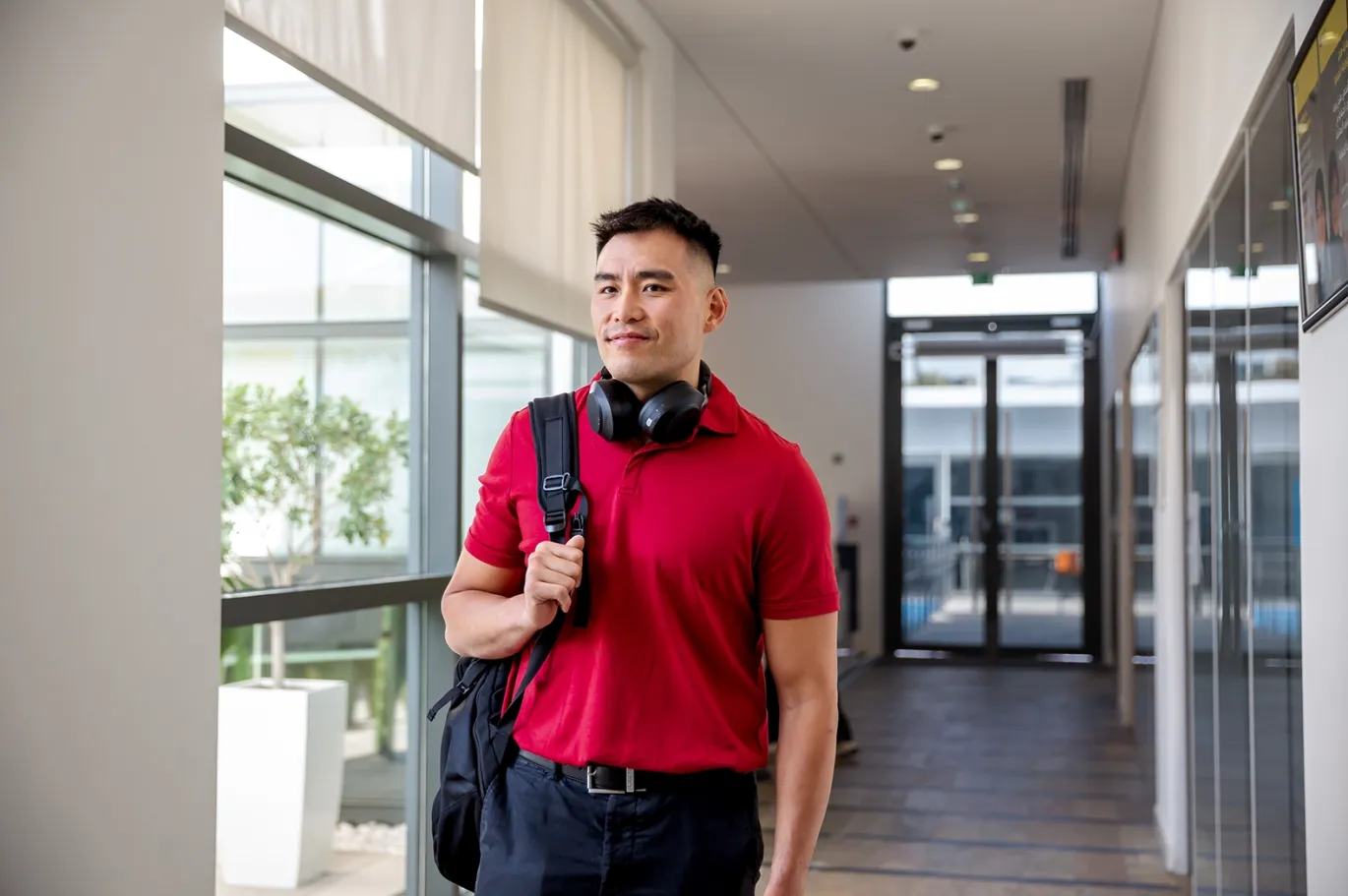 Young man with a backpack walking through an IELTS center hallway.