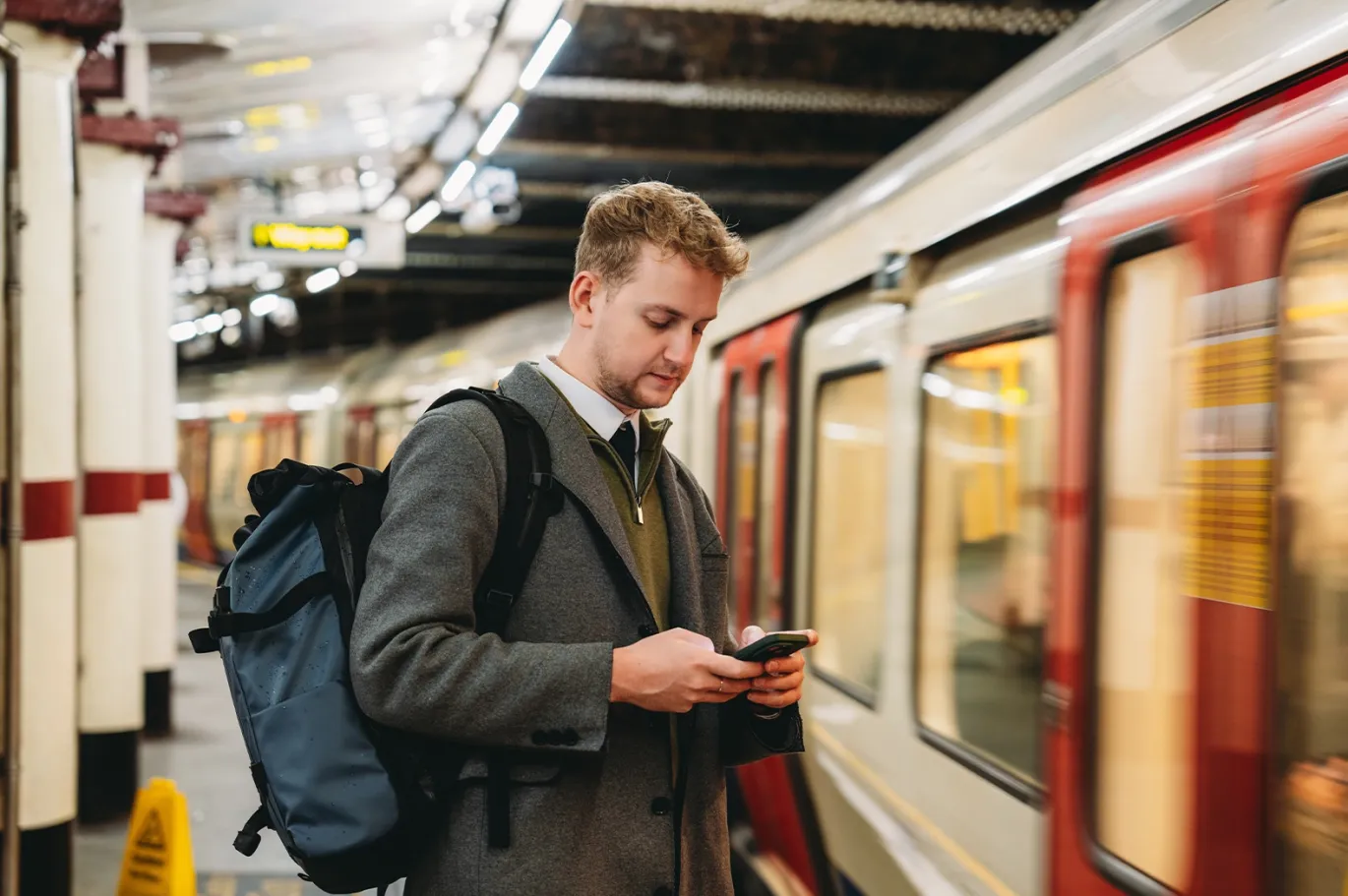 Young man using his mobile phone while waiting beside a metro train.