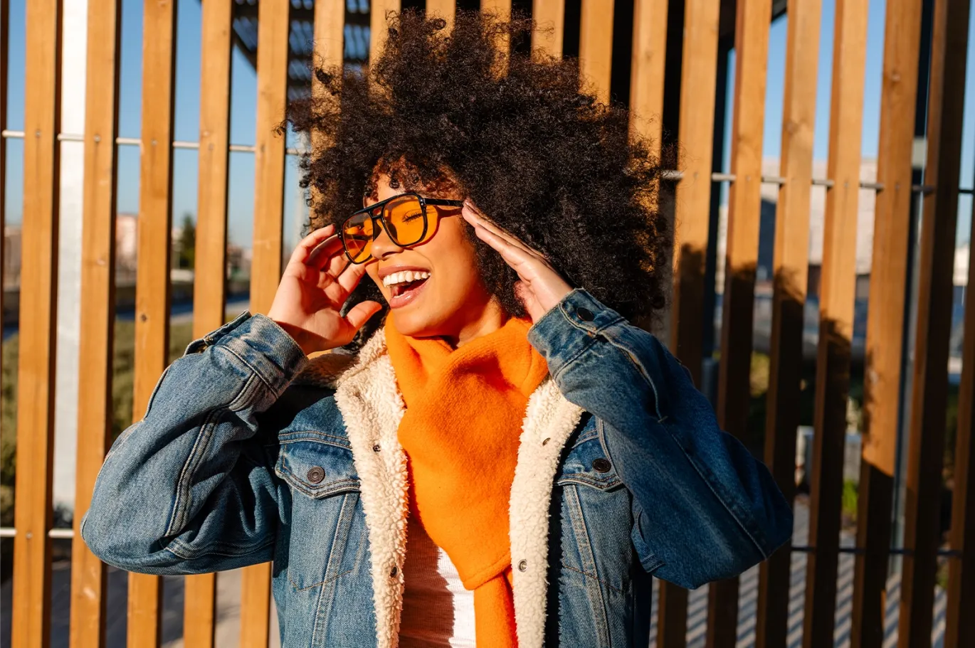 Young woman adjusting her sunglasses during sunset.