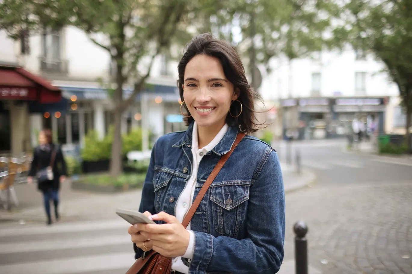 Young woman using her mobile phone while preparing for the IELTS exam outdoors.