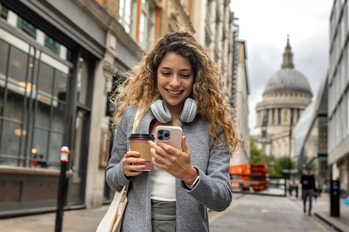Young woman using her mobile phone while standing on a European city street.