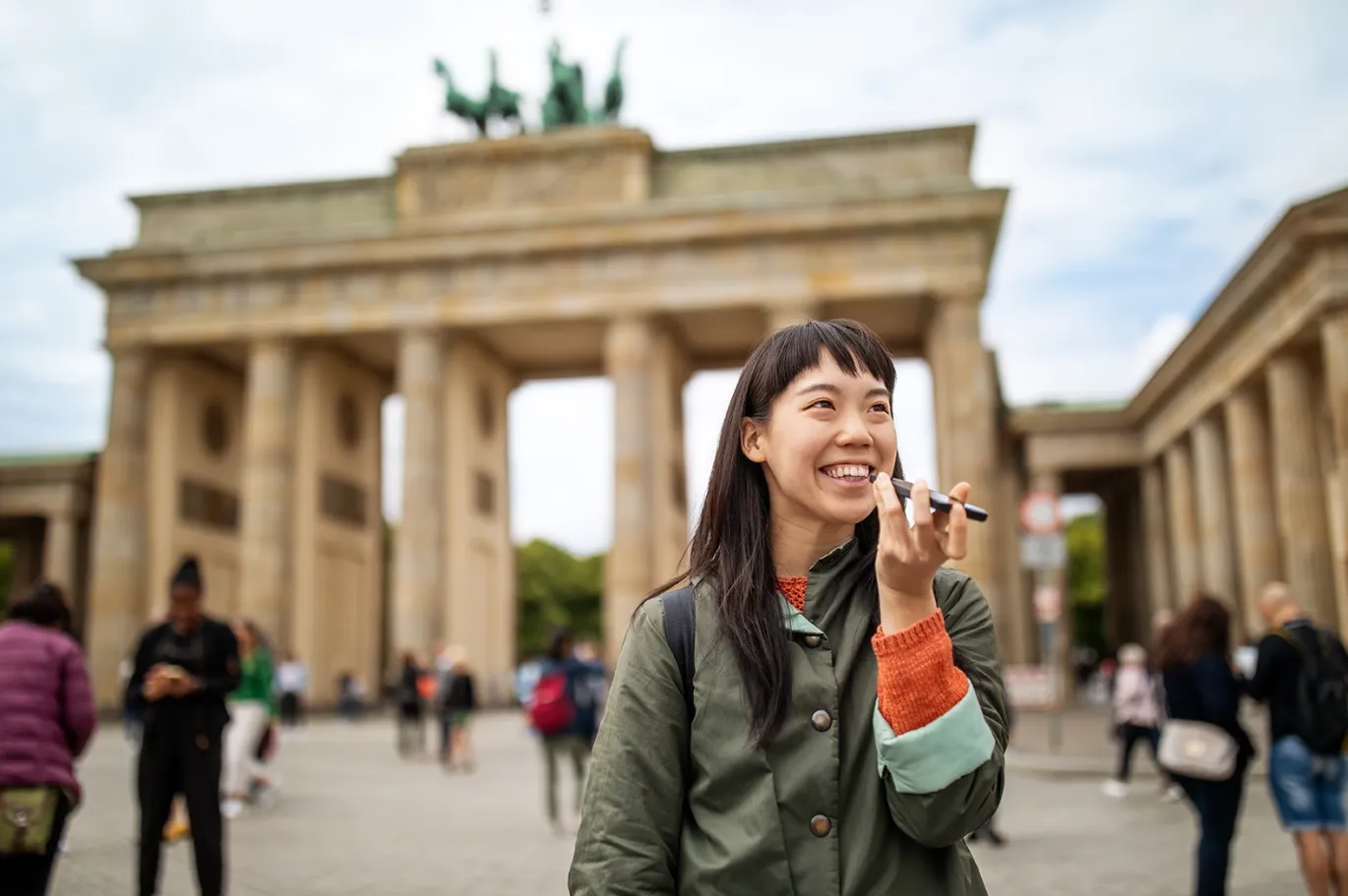 Young woman using her mobile phone while standing near the Brandenburg Gate in Berlin.