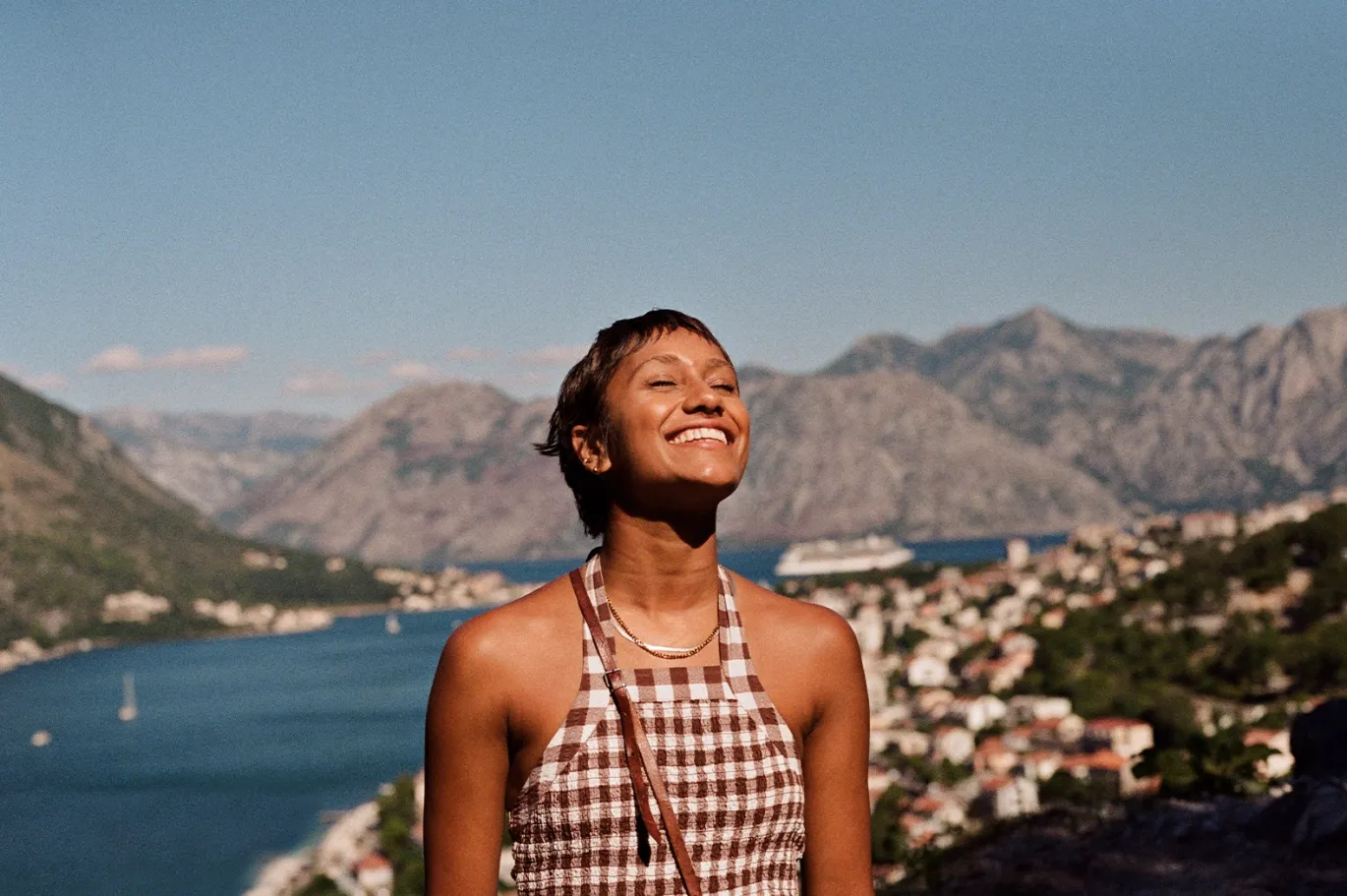 Young woman enjoying a scenic mountain and waterfront view outdoors.