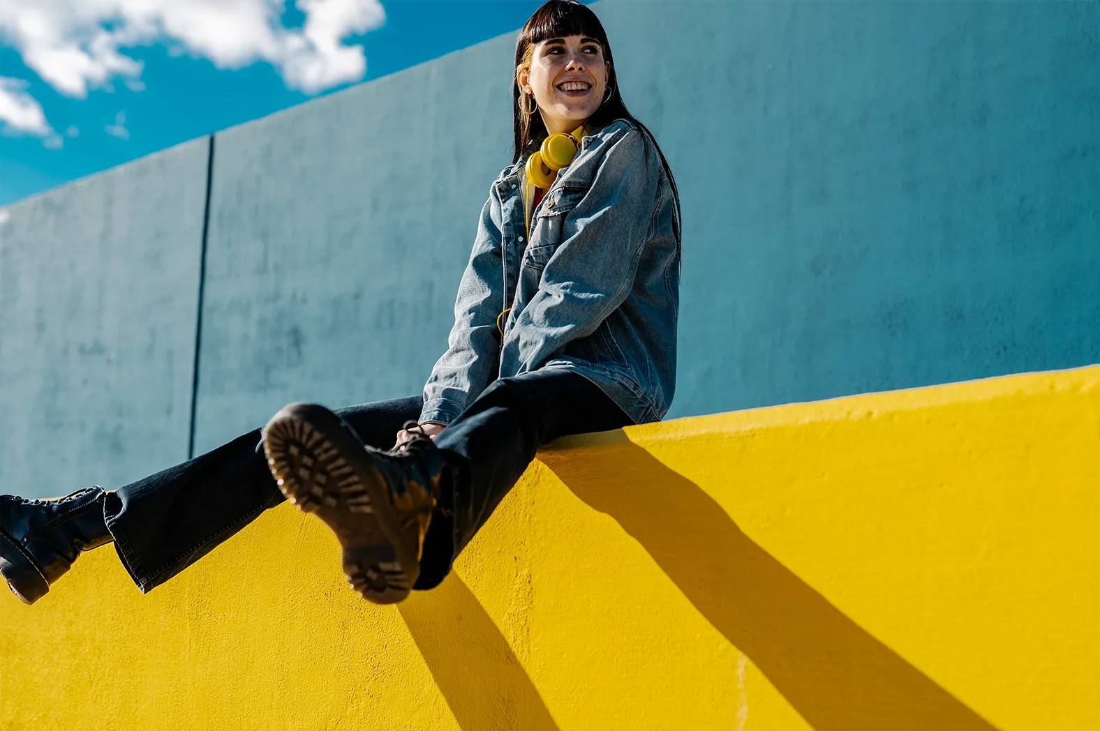Young woman sitting outdoors on a colorful wall