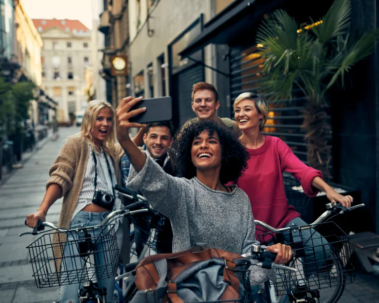 Group of friends taking selfie while exploring the city on a bicycle.