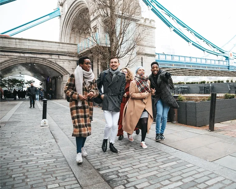 Group of friends walking together near Tower Bridge in London.