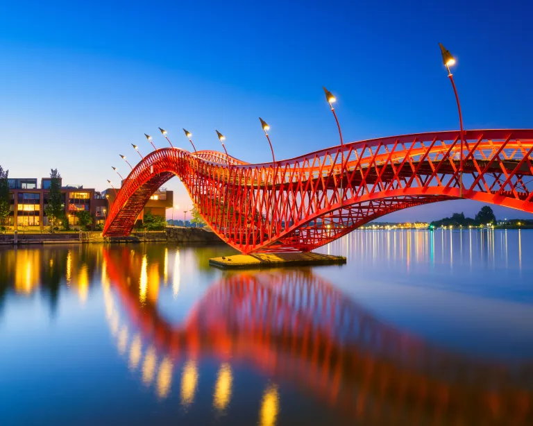 Modern bridge reflected on calm water during the evening.