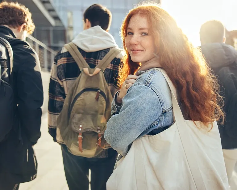 Student with a backpack smiling after attending an IELTS class.
