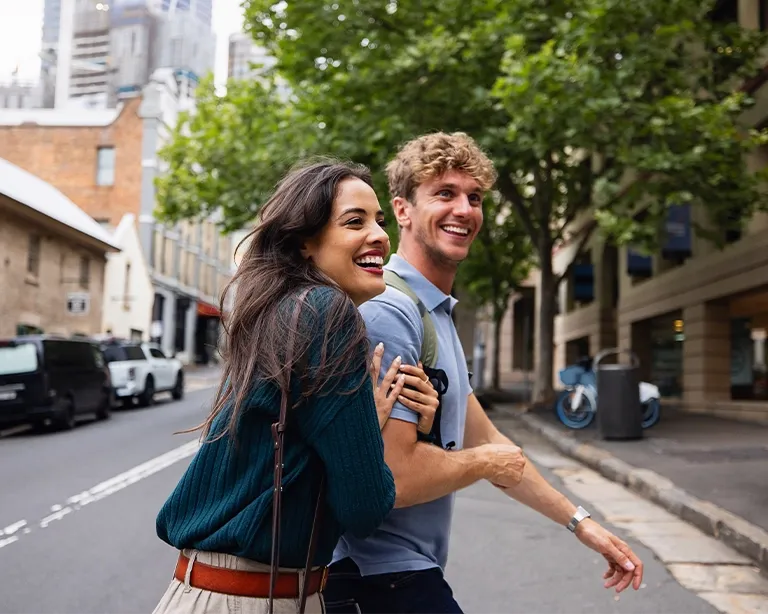 Two friends walking together and talking on a city street.