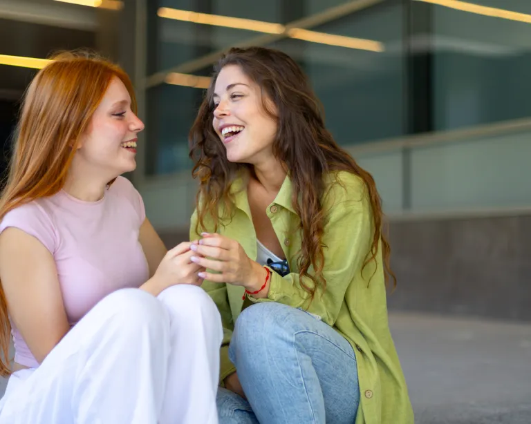 Two girls smiling at each other and discussing about IELTS exam
