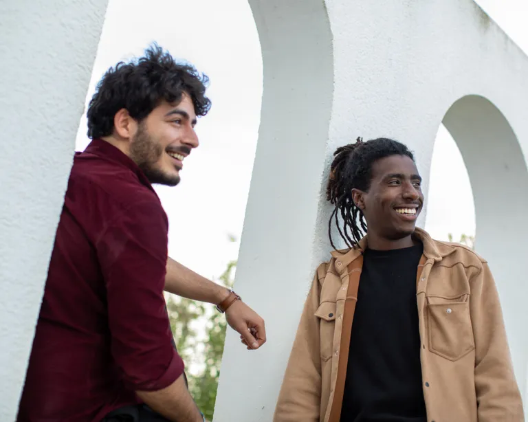 Two IELTS students walking and discussing their exam preparation near an IELTS center building.