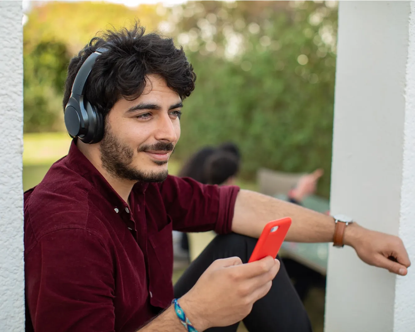 Young man wearing headphones and using his mobile phone while relaxing outdoors.