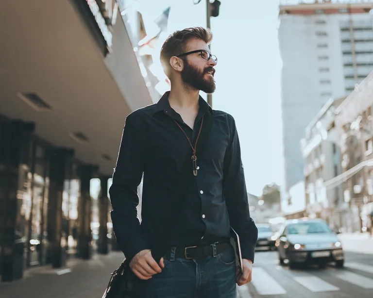 Young man with sunglasses walking through a city street.