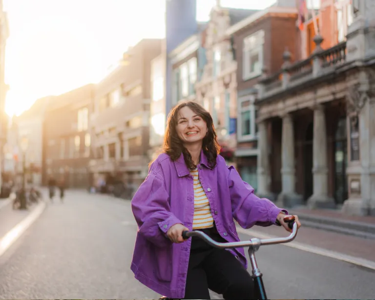Young woman riding a bicycle through a European city street.