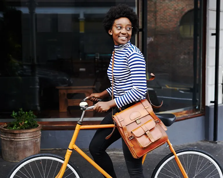 Young woman standing beside a bicycle outside a modern building.