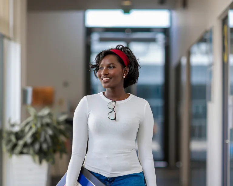 Young woman with headphones walking through an IELTS center hallway.