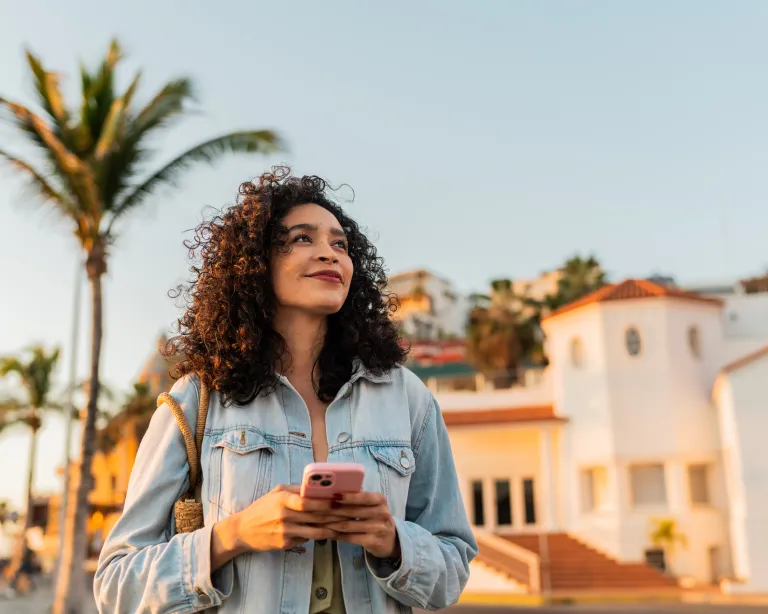 Young woman holding a mobile phone while standing.