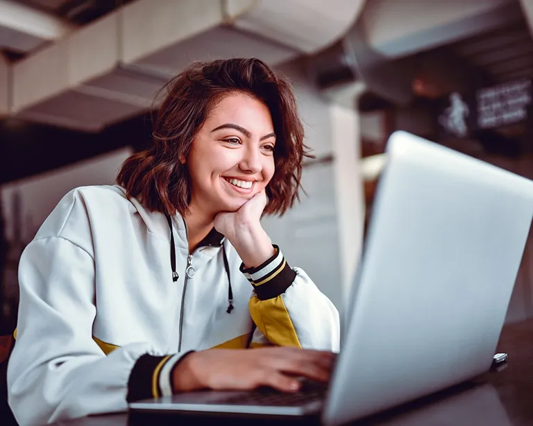 Young woman studying online for the IELTS exam using a laptop indoors.